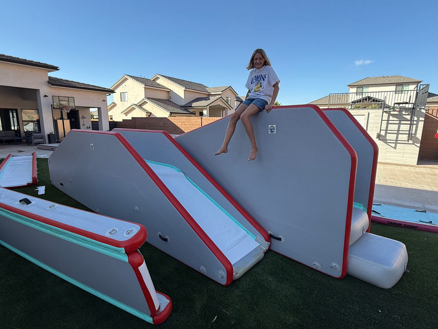 A long Swole Much Fun inflatable slip-and-slide set up across a sunny backyard